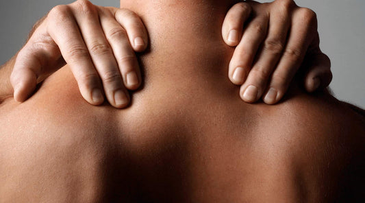 Person holding both shoulders from behind, illustrating rounded shoulder correction.