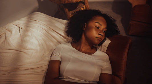 Woman lying down with distant gaze, suggesting mood and mental health impact from poor posture.
