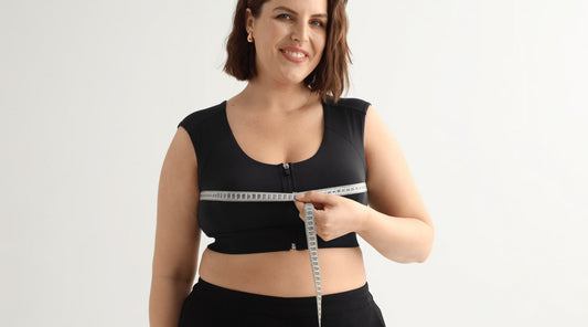 Measuring bust while wearing the black Etalon posture bra, demonstrating proper sizing for optimal back support.